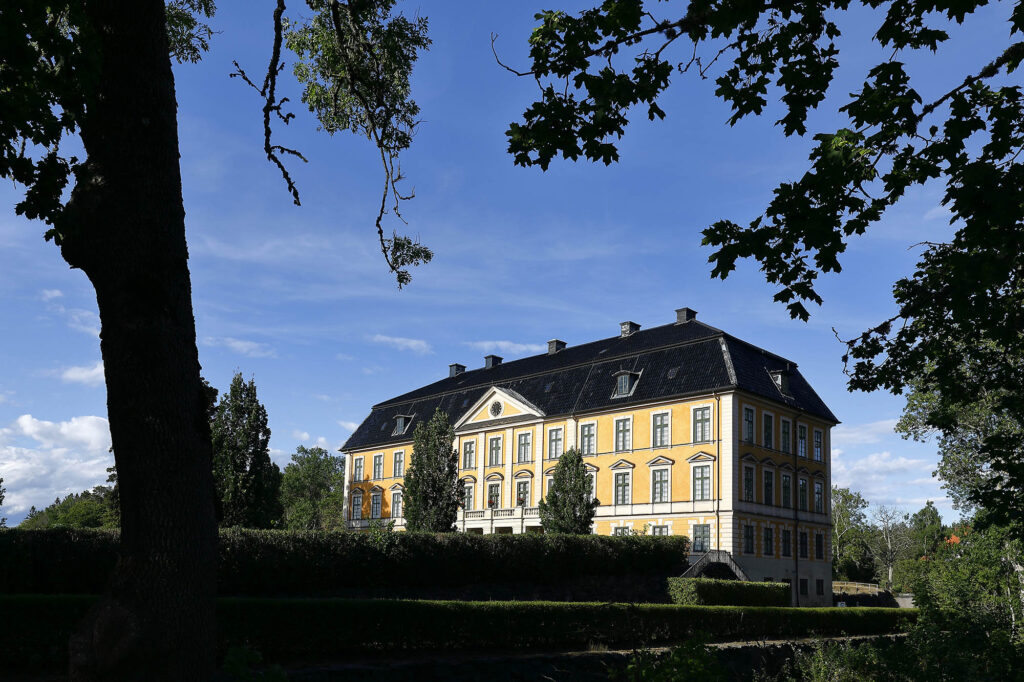 Gult slott med träd i förgrunden/Yellow castle with trees in the foreground