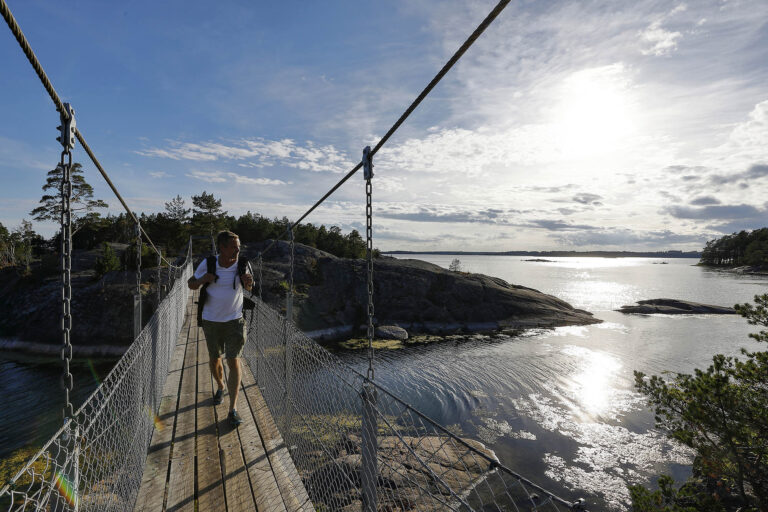 Man går över bro och tittar ut över havet/A man on a bridge