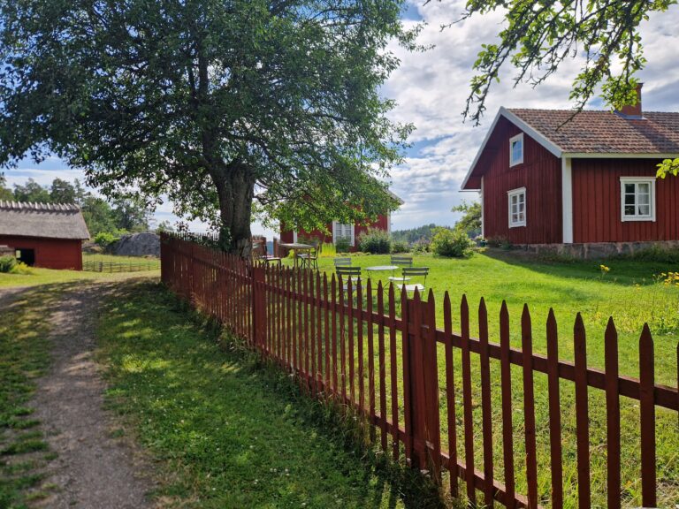 Rött staket, träd och rött gammalt torp.