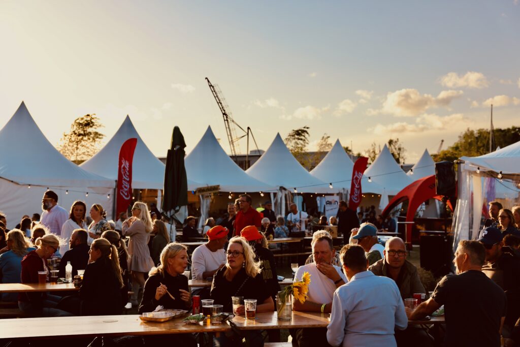 Människor som sitter vid bord utomhus på festivalområde