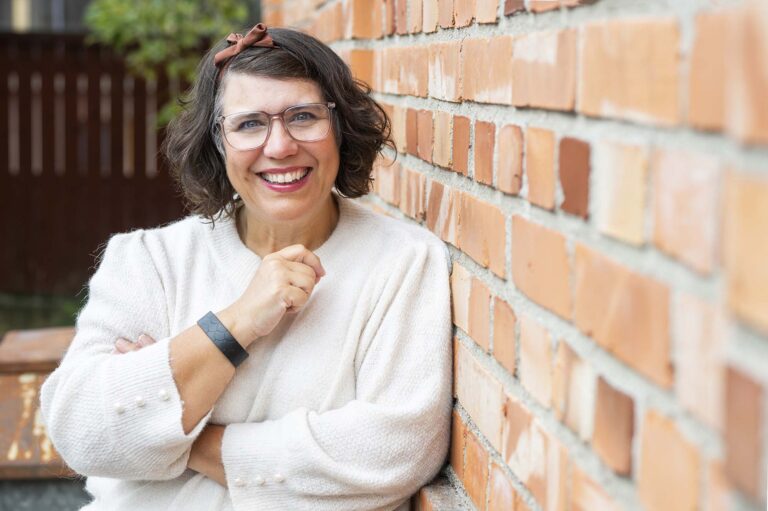 Kvinna lutar sig mot tegelvägg