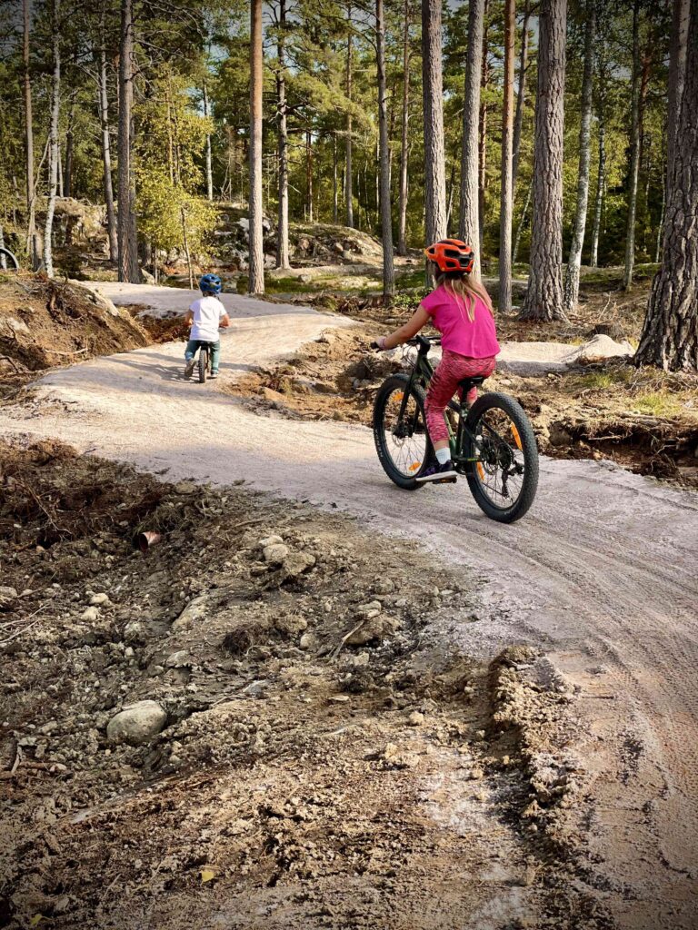 Barn som cyklar i skogen